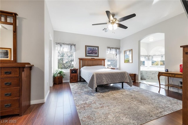 bedroom with multiple windows, connected bathroom, and dark wood-type flooring