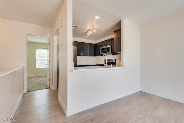 kitchen with light hardwood / wood-style flooring, stainless steel appliances, and kitchen peninsula