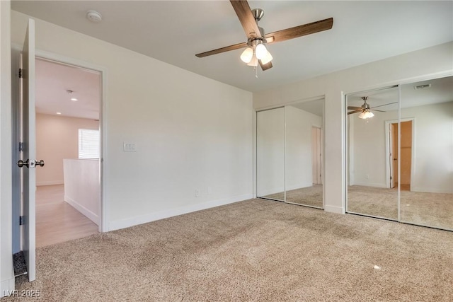 unfurnished bedroom featuring multiple closets, light colored carpet, and ceiling fan