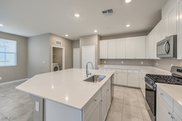 kitchen with sink, white cabinetry, stainless steel appliances, an island with sink, and washer / clothes dryer