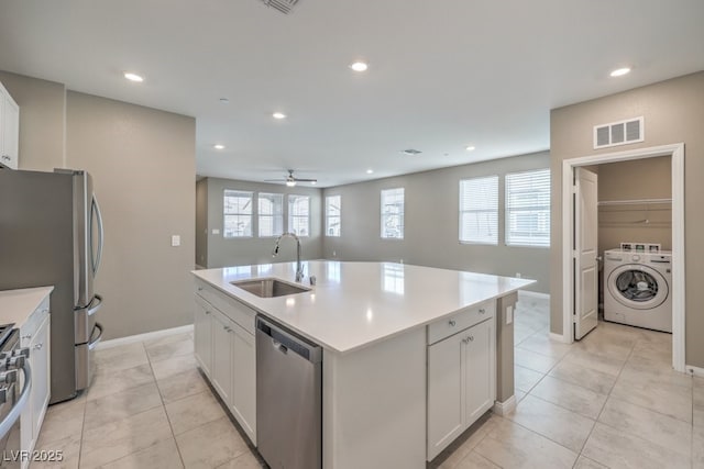 kitchen featuring sink, white cabinetry, a center island with sink, stainless steel appliances, and washer / clothes dryer