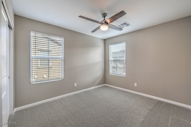 empty room with ceiling fan, carpet floors, visible vents, and baseboards