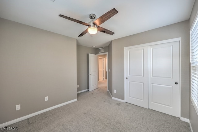 unfurnished bedroom featuring ceiling fan, a closet, and light carpet