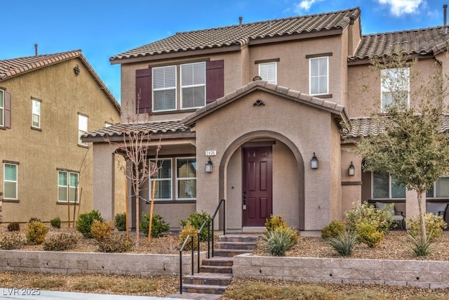 mediterranean / spanish home featuring a tiled roof and stucco siding