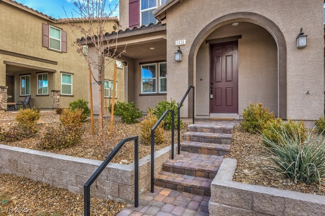 view of exterior entry with a tile roof and stucco siding