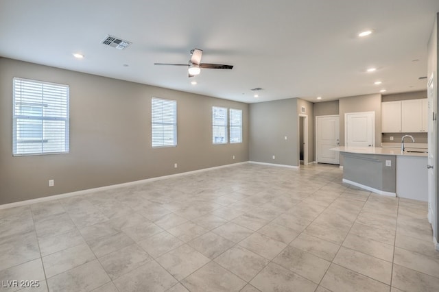 unfurnished living room featuring recessed lighting, visible vents, a ceiling fan, a sink, and baseboards