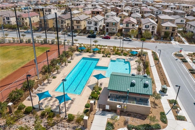 community pool with a patio area, fence, and a residential view