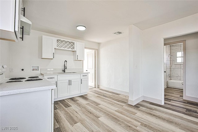 kitchen with white cabinets, light hardwood / wood-style floors, sink, and range with electric stovetop