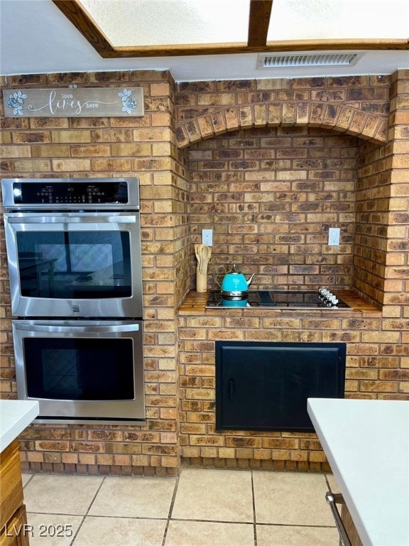 kitchen featuring tile patterned floors, stainless steel double oven, visible vents, and light countertops