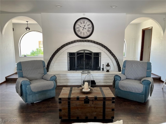 living room with hardwood / wood-style floors, a fireplace, baseboards, and arched walkways