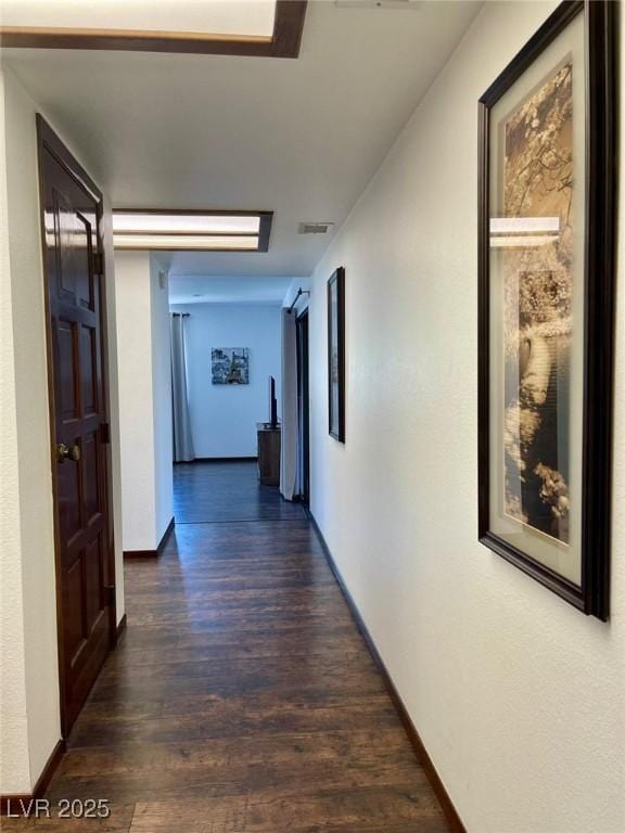 corridor with dark wood finished floors, visible vents, and baseboards