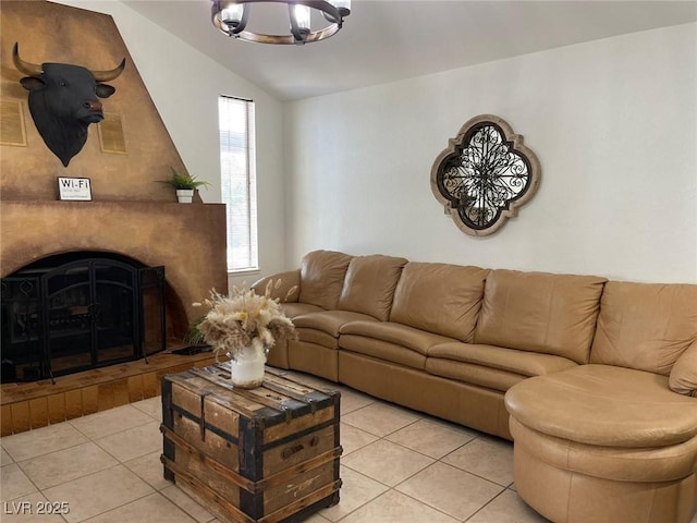 living area with vaulted ceiling, a fireplace with raised hearth, light tile patterned floors, and a chandelier