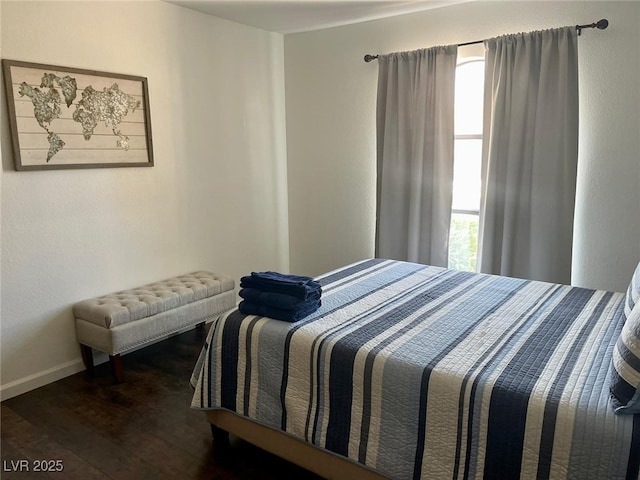 bedroom featuring multiple windows, baseboards, and wood finished floors