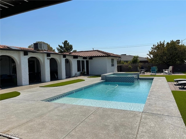 view of swimming pool featuring a patio area, fence, a pool with connected hot tub, and central air condition unit