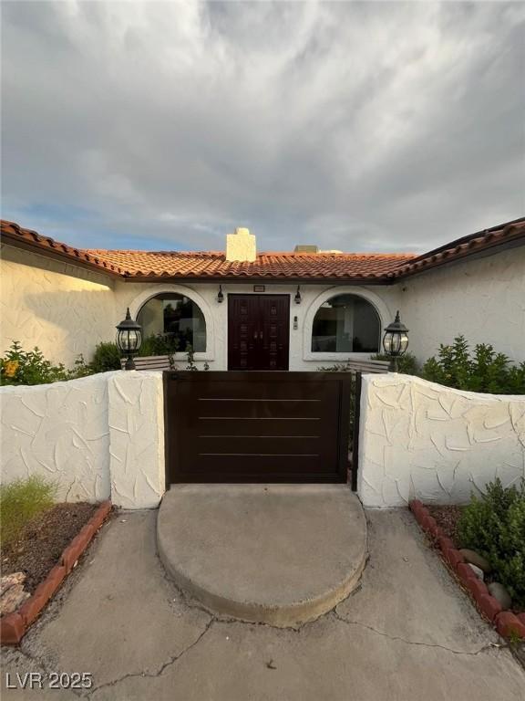 view of front facade featuring driveway, a fenced front yard, a tile roof, an attached garage, and stucco siding