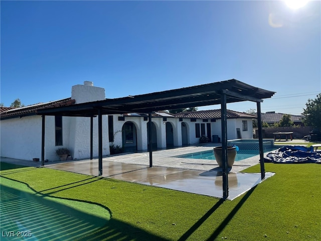back of property with a chimney, a patio, a lawn, and stucco siding