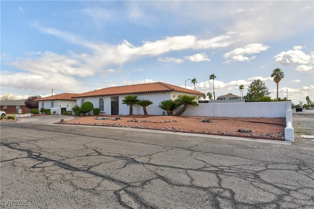 mediterranean / spanish-style home featuring stucco siding, driveway, a tiled roof, and fence