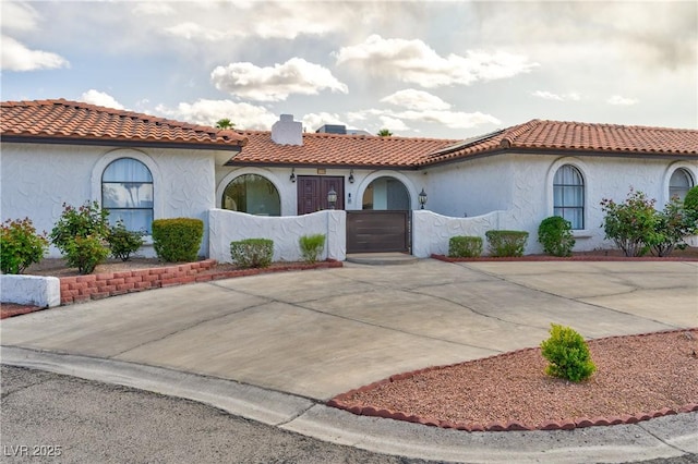 mediterranean / spanish-style home with an attached garage, a tiled roof, driveway, and stucco siding