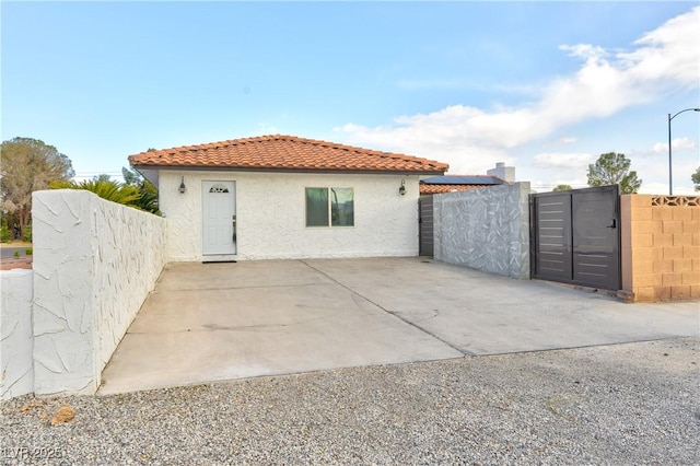 exterior space featuring a gate, fence, a tiled roof, and stucco siding