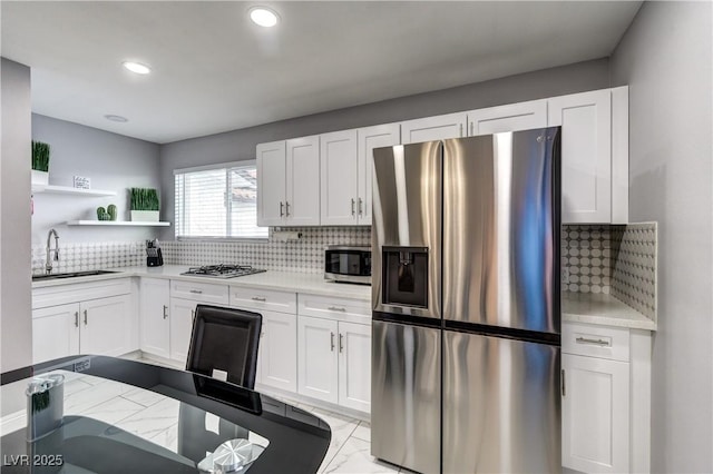 kitchen with open shelves, decorative backsplash, stainless steel appliances, and a sink