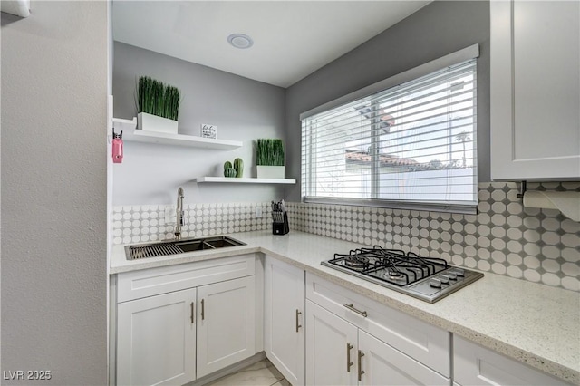 kitchen with white cabinets, a sink, tasteful backsplash, stainless steel gas stovetop, and open shelves