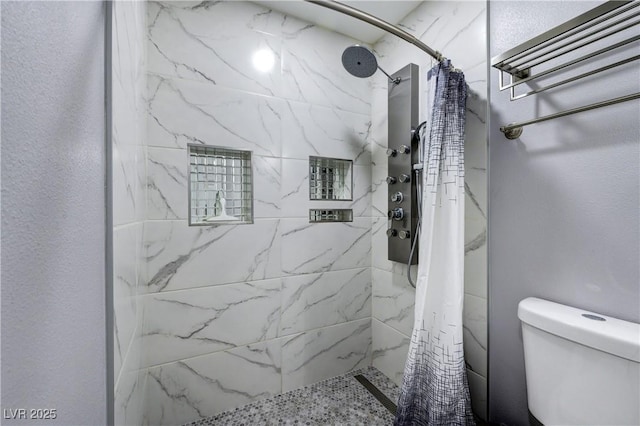 bathroom featuring toilet and a tile shower