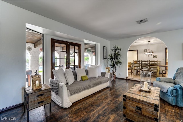 living room with french doors, arched walkways, visible vents, baseboards, and wood finished floors
