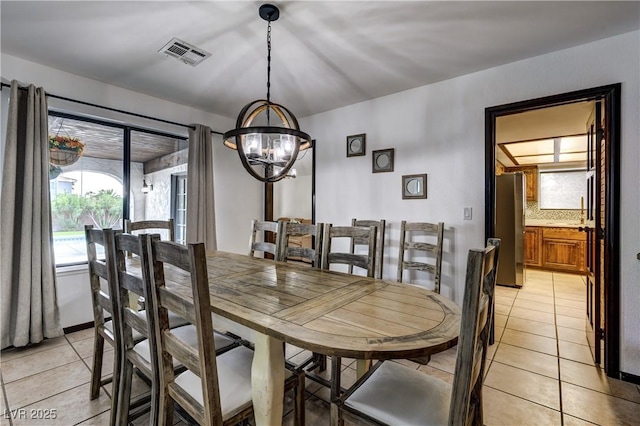 dining area featuring visible vents, a notable chandelier, and light tile patterned floors