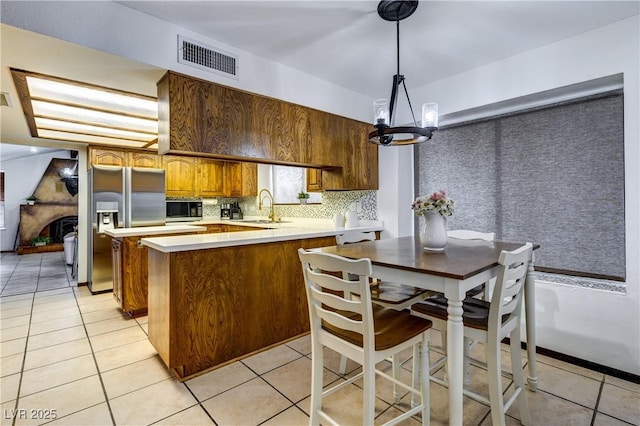 kitchen with a sink, light tile patterned flooring, an inviting chandelier, appliances with stainless steel finishes, and visible vents