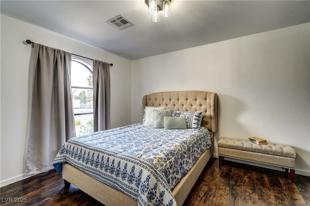 bedroom with baseboards, wood finished floors, and visible vents
