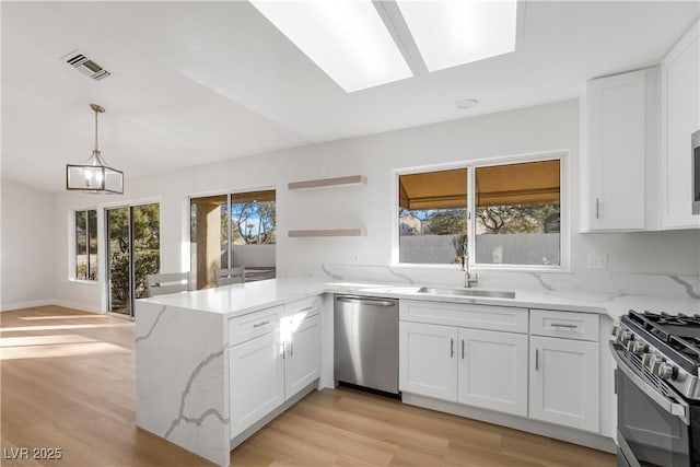 kitchen featuring white cabinetry, kitchen peninsula, light stone countertops, and stainless steel appliances