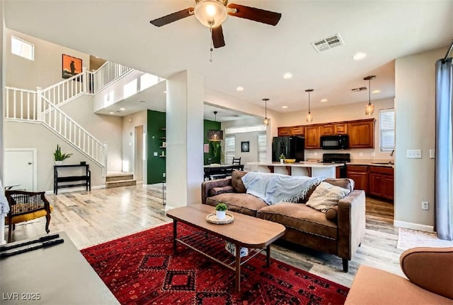 living room featuring ceiling fan, sink, and light wood-type flooring