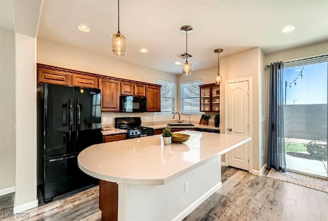 kitchen featuring sink, hanging light fixtures, plenty of natural light, a kitchen island, and black appliances