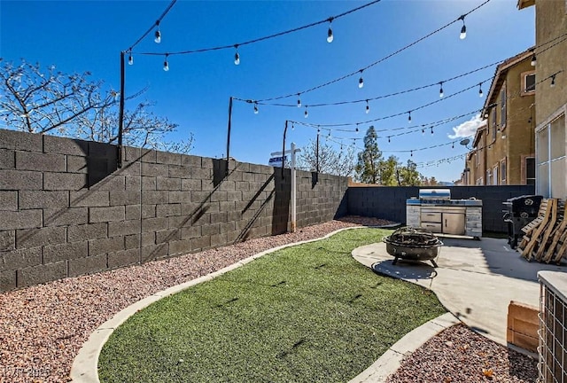 view of yard featuring an outdoor kitchen, a patio area, and a fire pit