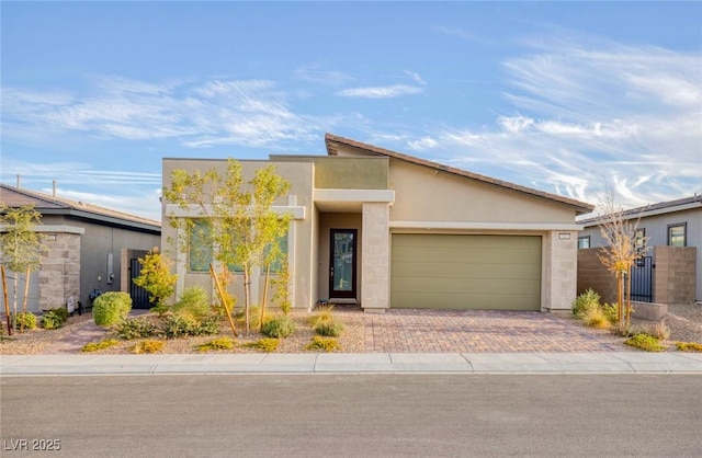 view of front of home featuring decorative driveway, fence, a garage, and stucco siding