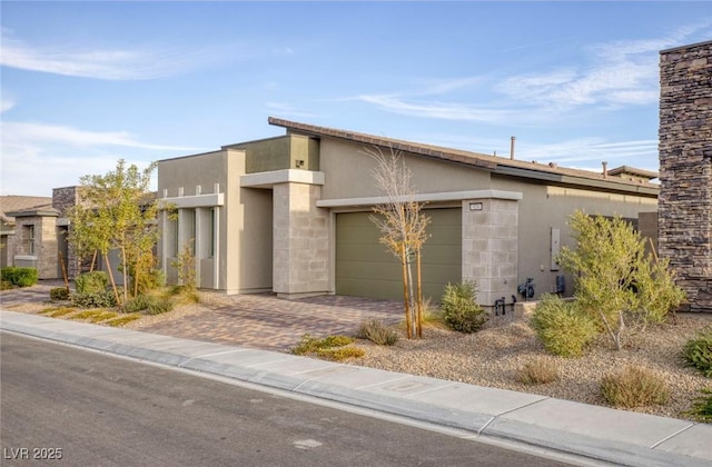 view of front of home featuring a garage, decorative driveway, and stucco siding