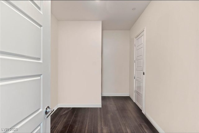 unfurnished room featuring baseboards and dark wood-style flooring