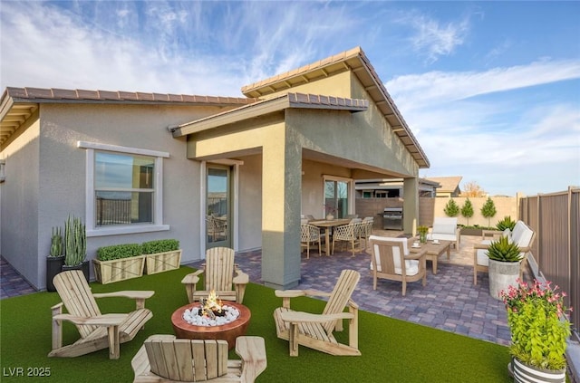 rear view of property featuring a patio area, a fire pit, stucco siding, and fence