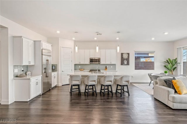 kitchen featuring stainless steel appliances, a breakfast bar area, open floor plan, and light countertops