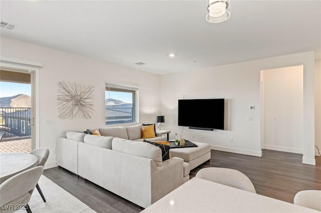 living area featuring visible vents, baseboards, and dark wood-type flooring