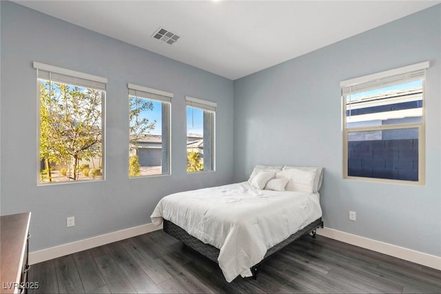 bedroom with visible vents, baseboards, and wood finished floors