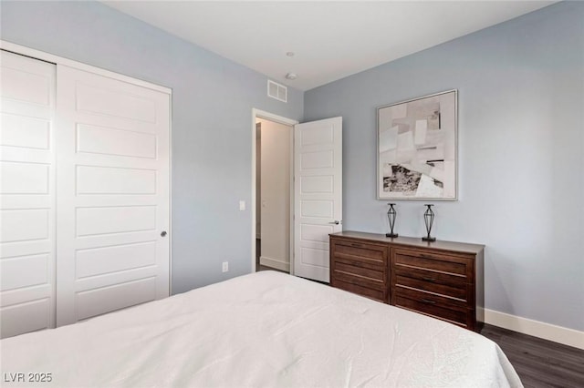 bedroom featuring a closet, visible vents, dark wood-type flooring, and baseboards