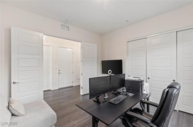 home office with dark wood-type flooring and visible vents