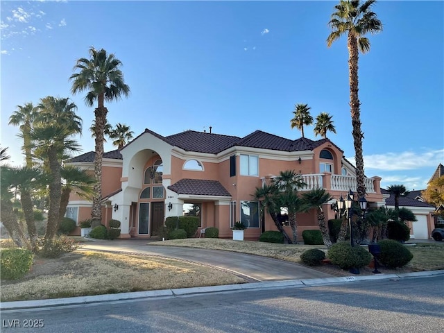 mediterranean / spanish-style home featuring a tile roof, driveway, and stucco siding