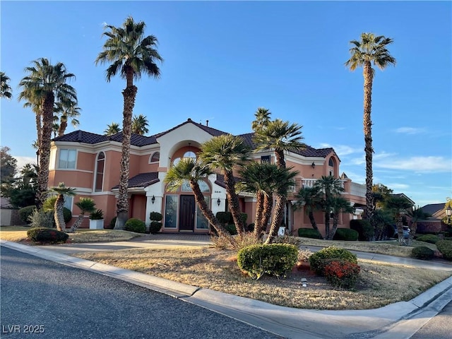 mediterranean / spanish-style home with driveway, a tile roof, and stucco siding