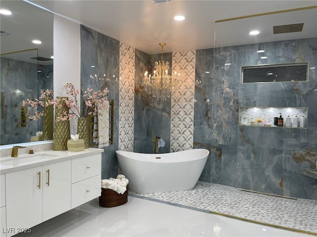 bathroom featuring vanity, tile walls, a notable chandelier, and a bathtub