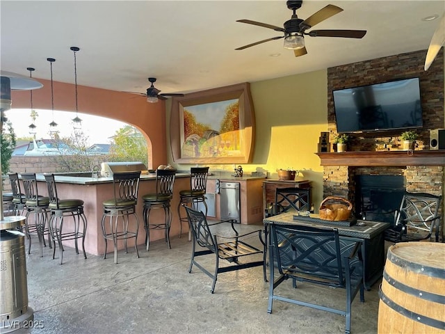 bar featuring concrete flooring, a fireplace, and ceiling fan