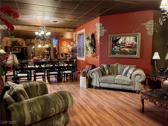 living area featuring a paneled ceiling, visible vents, a chandelier, and wood finished floors