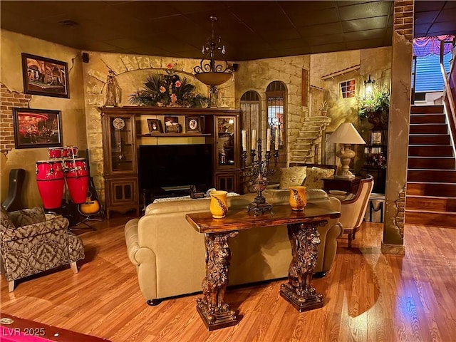 interior space featuring arched walkways, stairway, a drop ceiling, and wood finished floors