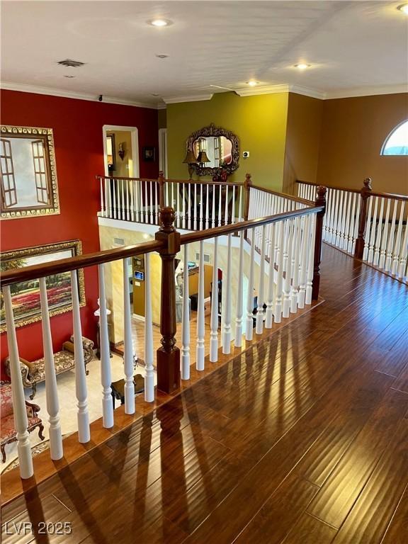 hall featuring ornamental molding, visible vents, and wood finished floors